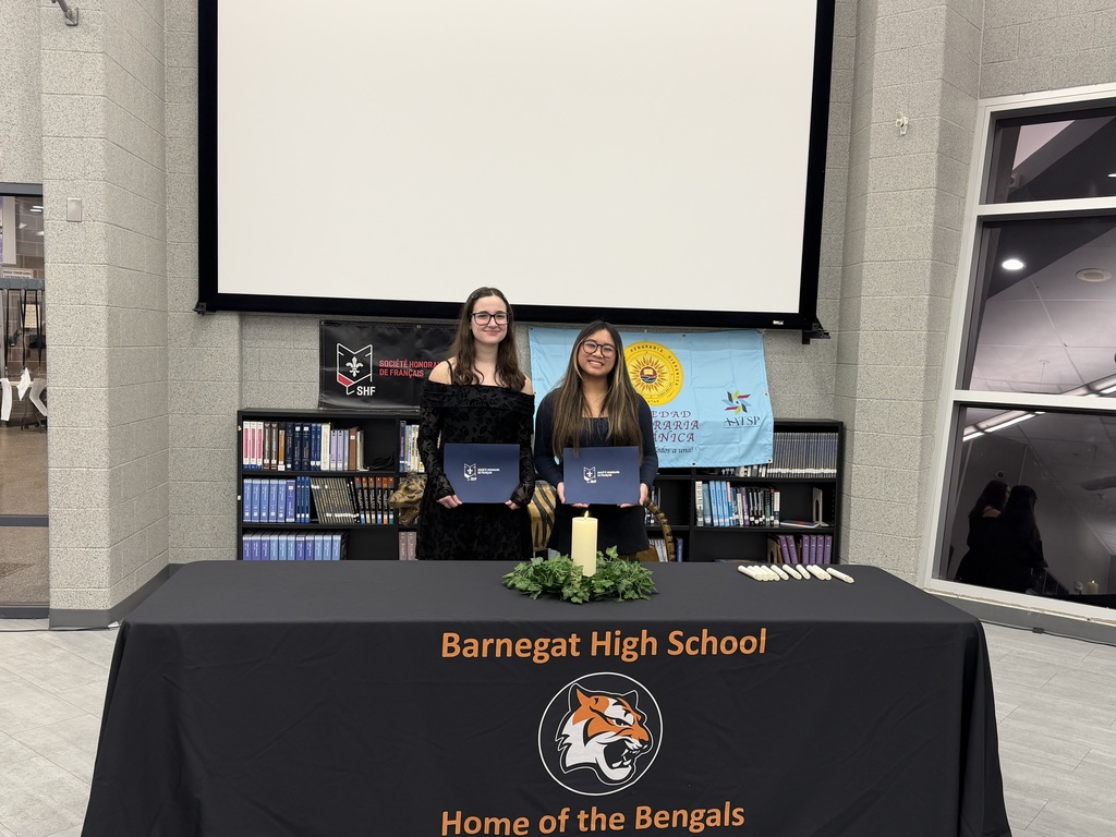 Image of the two female students holding their certificates behind a table with candles. 