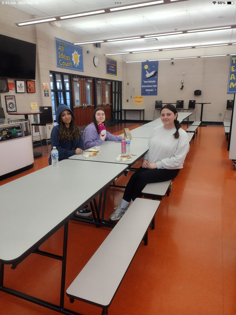 Three female students sitting at the table eating bagels together. 