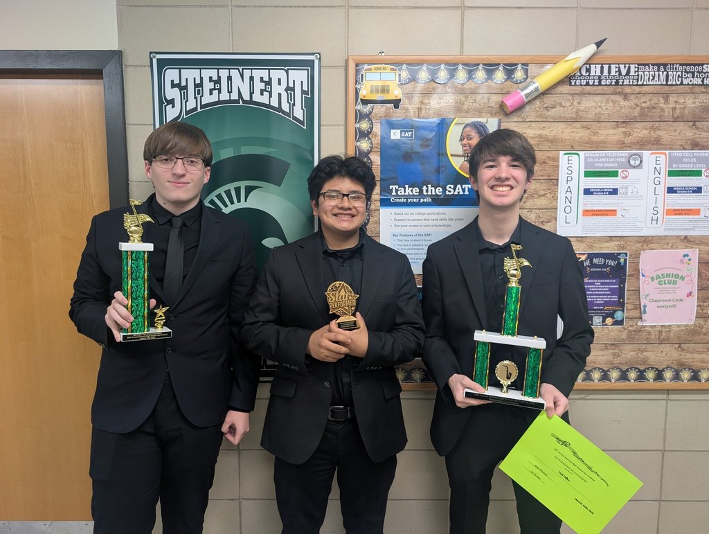 Image of three jazz ensemble members posing on a wall holding the trophies and certificate won at the festival. 