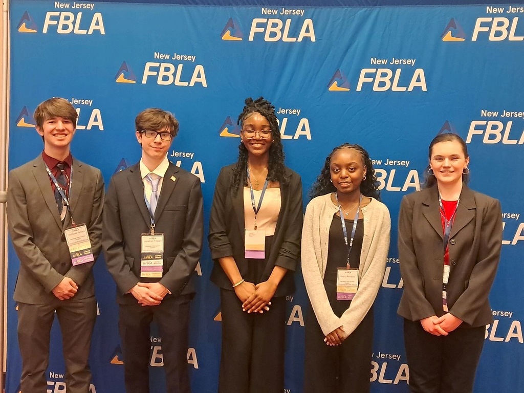 Image of the five FBLA Club members posing in front of the NJ FBLA banner all dressed up wearing their credentials around their necks. 