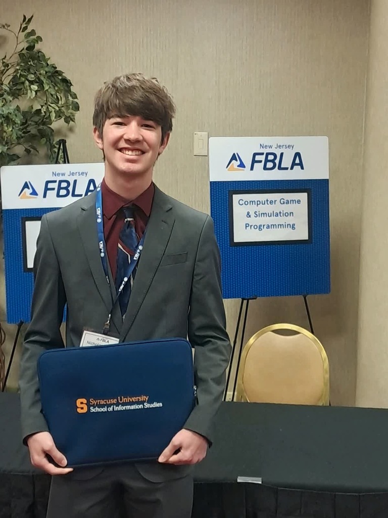 Image of Nick Sellers posing in front of the NJ FBLA Computer Game & Simulation Programming easel. 