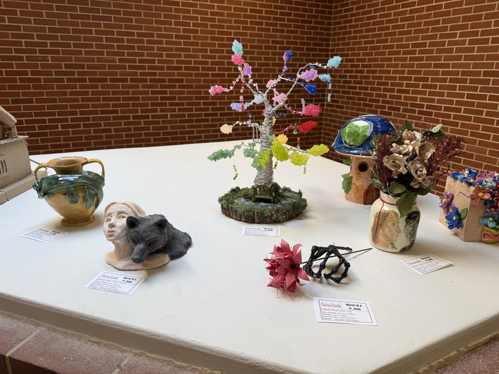 Image of the ceramic pieces that were created on display on a table with information cards next to each piece. 