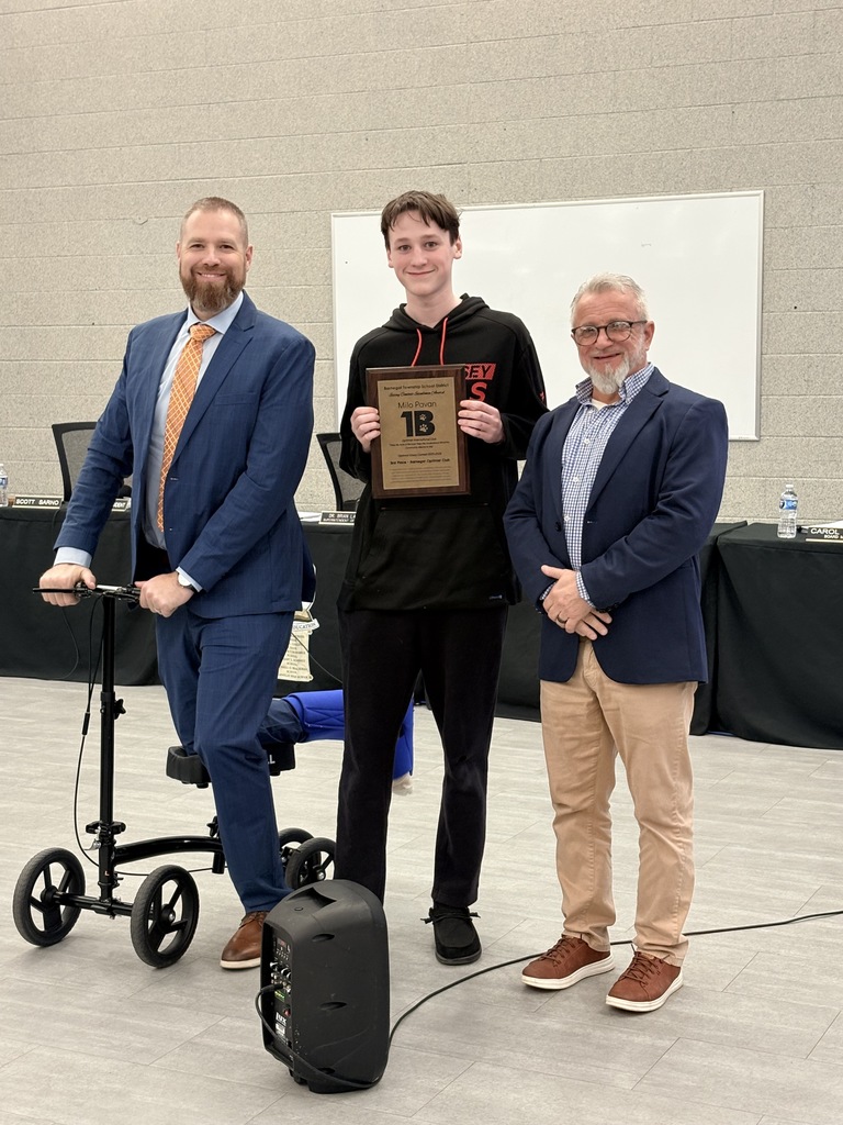 Image of Milo holding a plaque and posing with the Superintendent and Board President. 