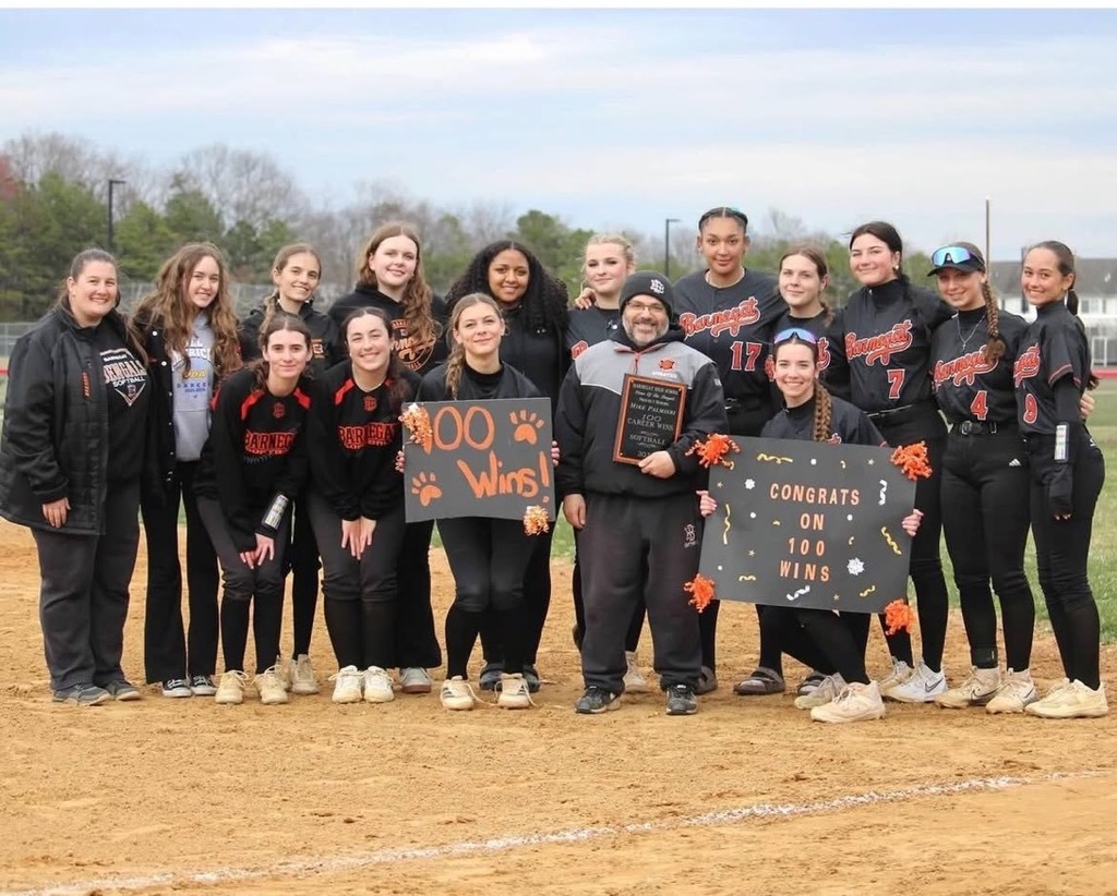 Image of Coach Palmieri holding a plaque surrounded by the assistant coach and players holding signs of congratulations. 
