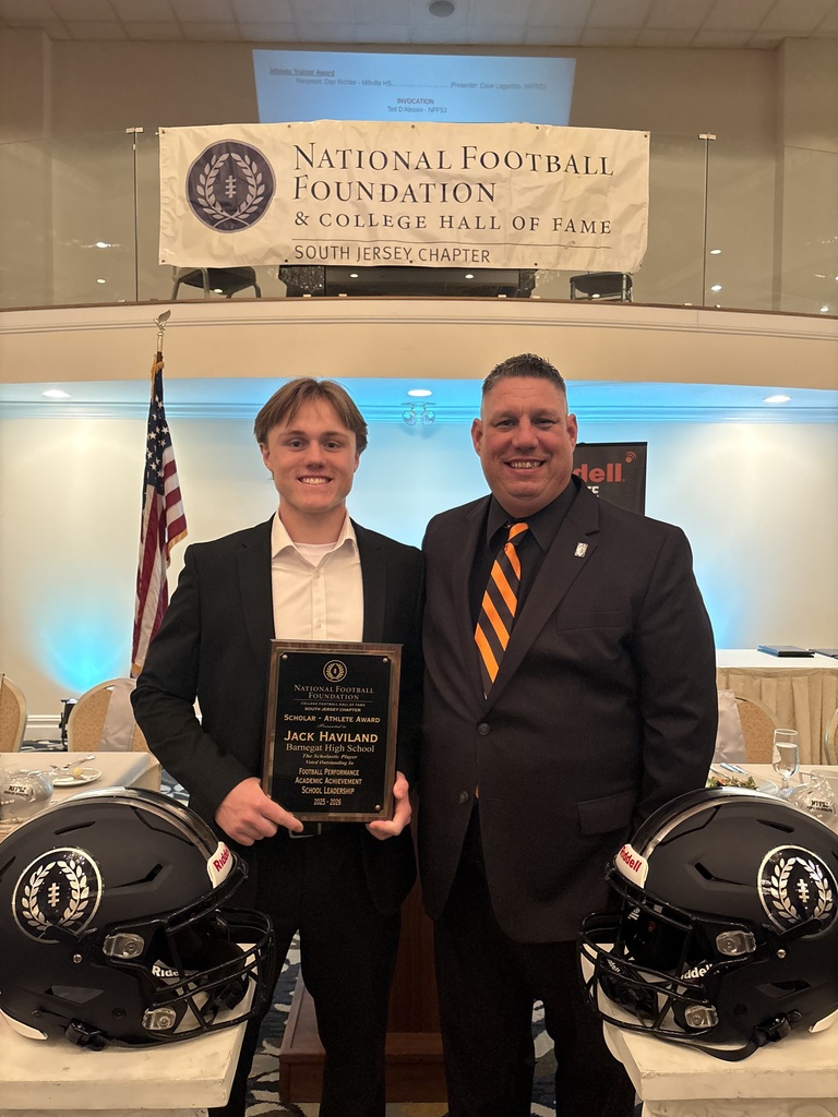 Image of Jack holding a plaque posing with the Athletic Director. 