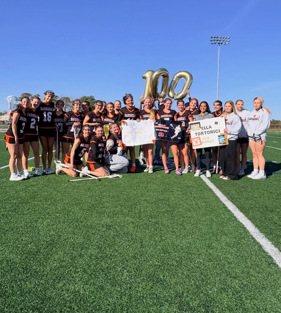 Image of the girls lacrosse team hold signs and balloons in support of Ella's 100th goal. 