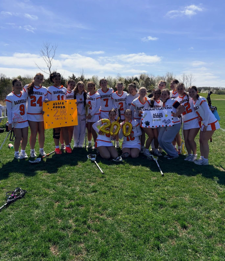 Image of the girls lacrosse team hold signs and balloons in support of Allie's 200th save. 