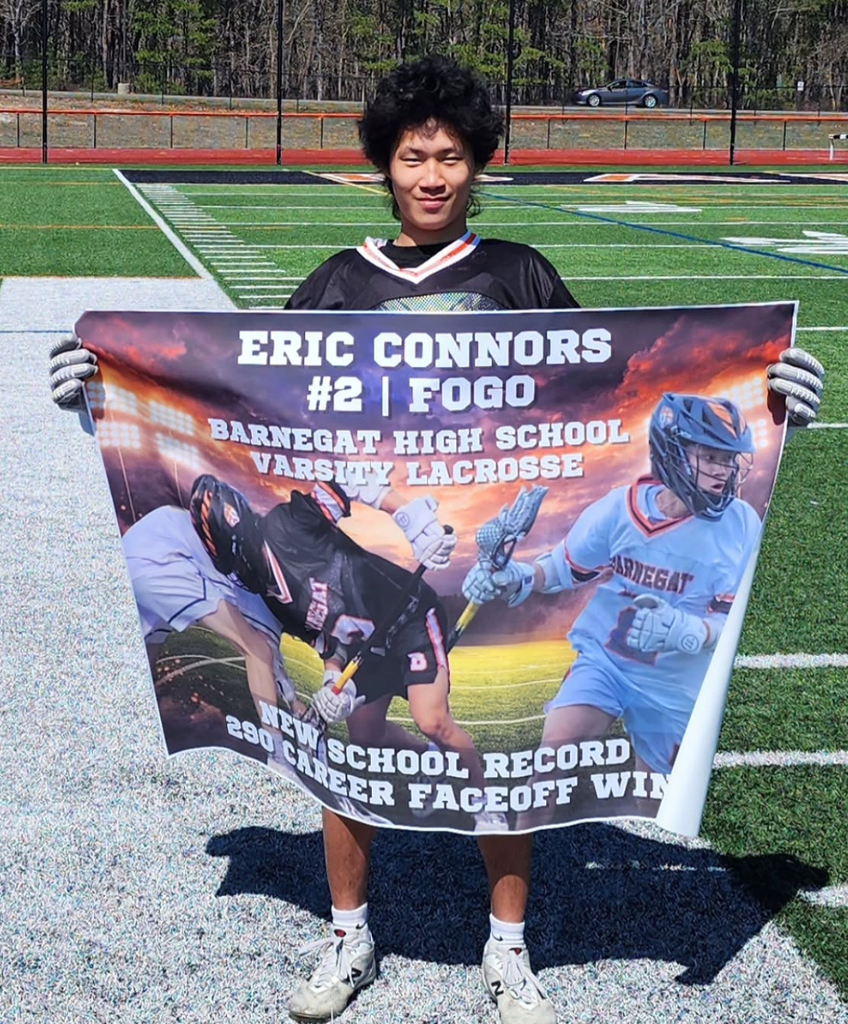 Image of Eric holding a sign with three different pictures of himself that states Eric Connors #2 FOGO BHS Varsity Lacrosse New School Record 290 Career Faceoff Wins. 