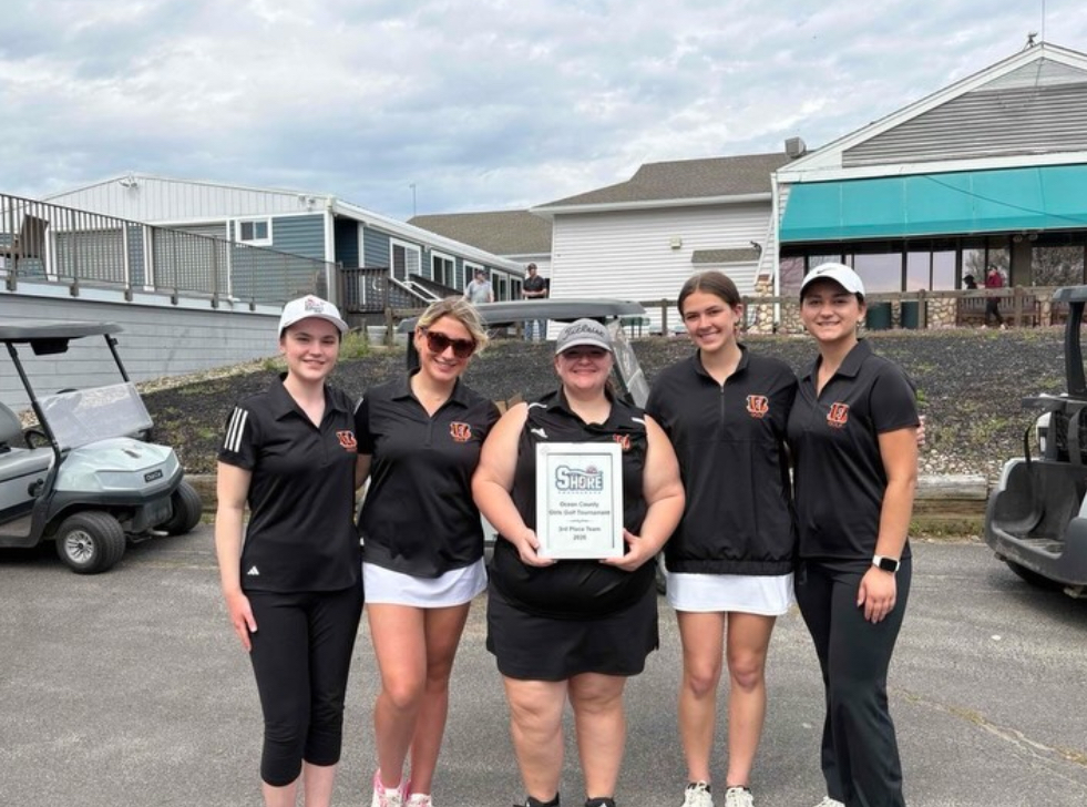 Image of the five girls golfers posing together while the one in the middle holds a plaque.  