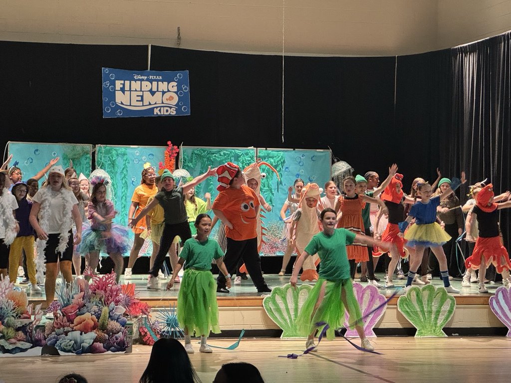 Image of the cast members performing a scene on stage from the play. 