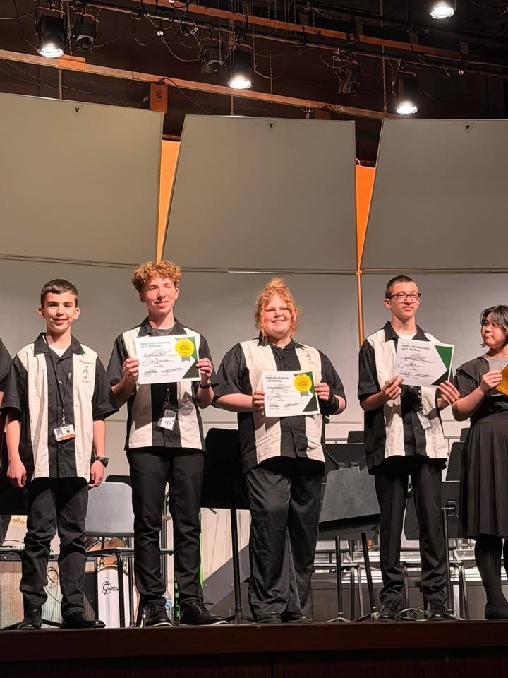 Image of Rex and the Saxophone section posing on stage while holding their certificates. 