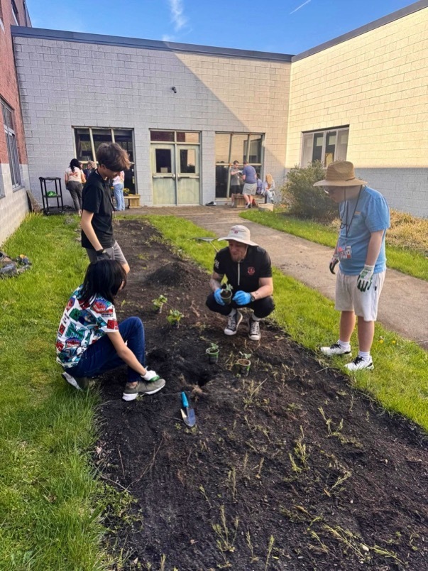 Image of the MD students and staff planting in the garden bed. 