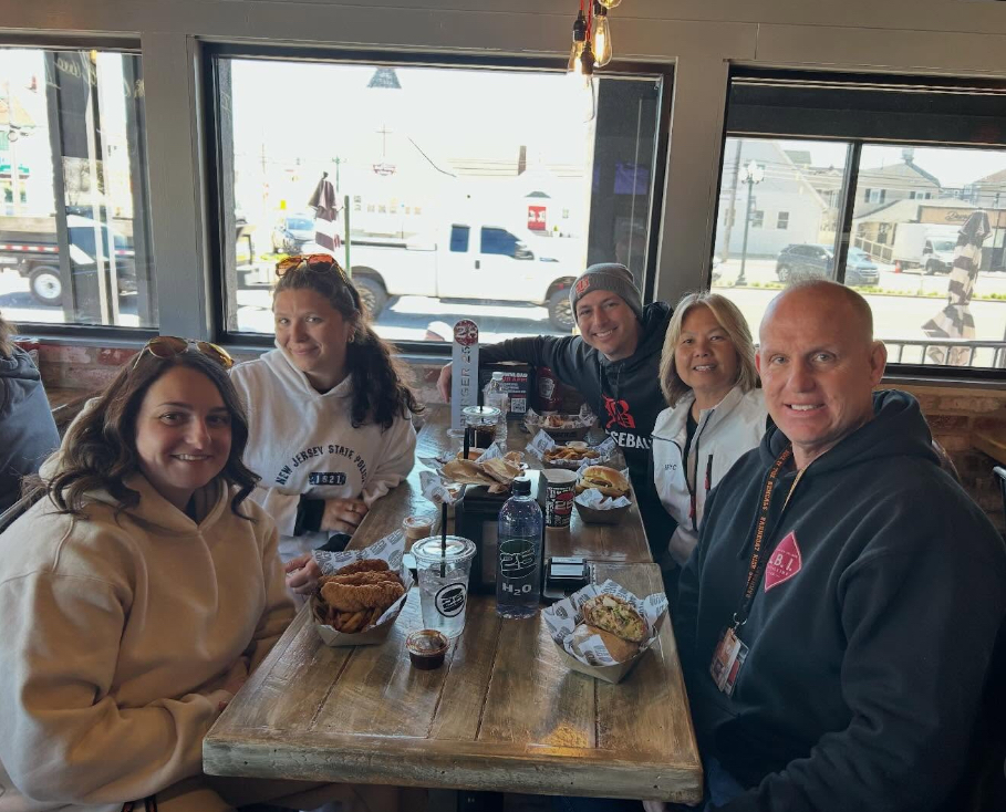 Image of five staff members sitting in a booth at Burger 25 with their meals on the table. 