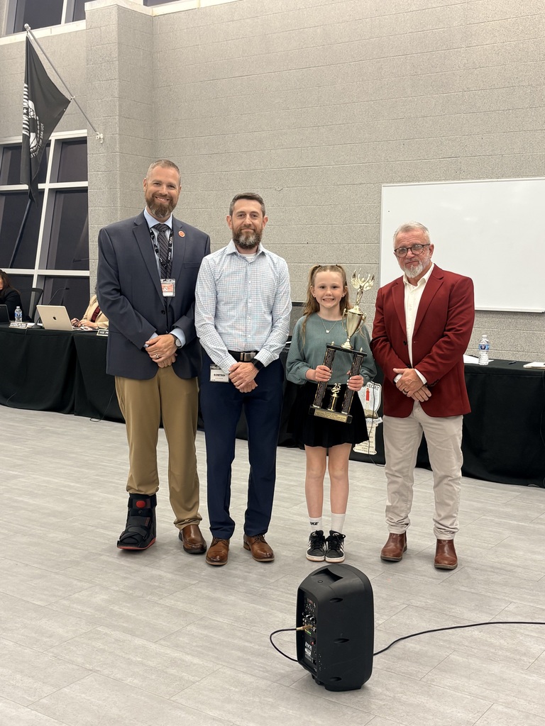 Image of Kennedy holding her trophy and posing with the Superintendent, BOE President, and her teacher. 