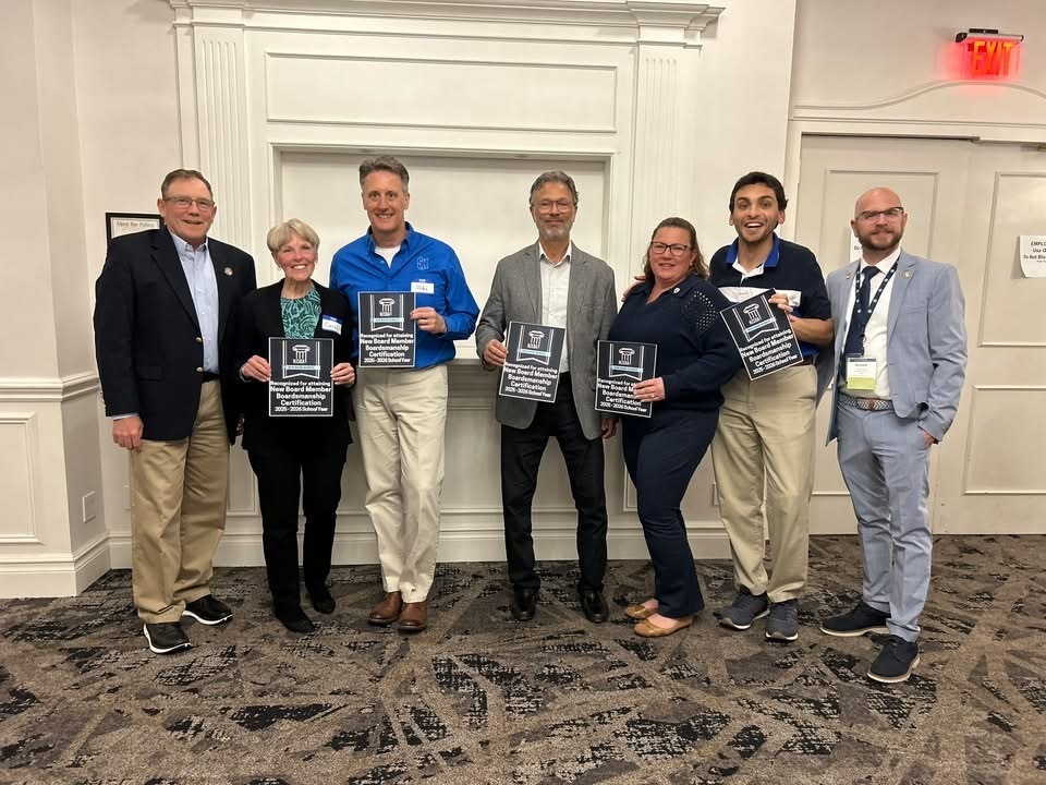 Image of two BOE members holding plaques with three other Ocean County BOE members standing in between two School Boards members.