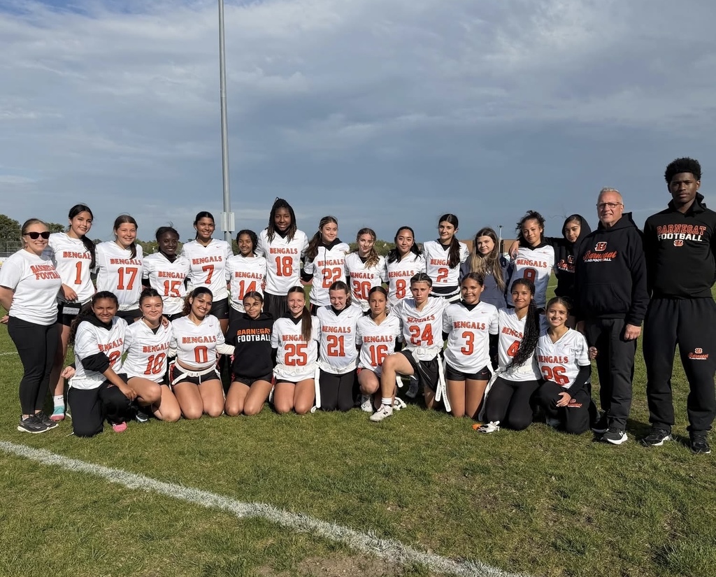 Image of the girls  flag football team posing with the coaches on the field after their Championship win.