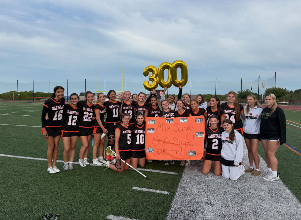 Image of the girls lacrosse team hold signs and balloons in support of Allie's 300th save. 
