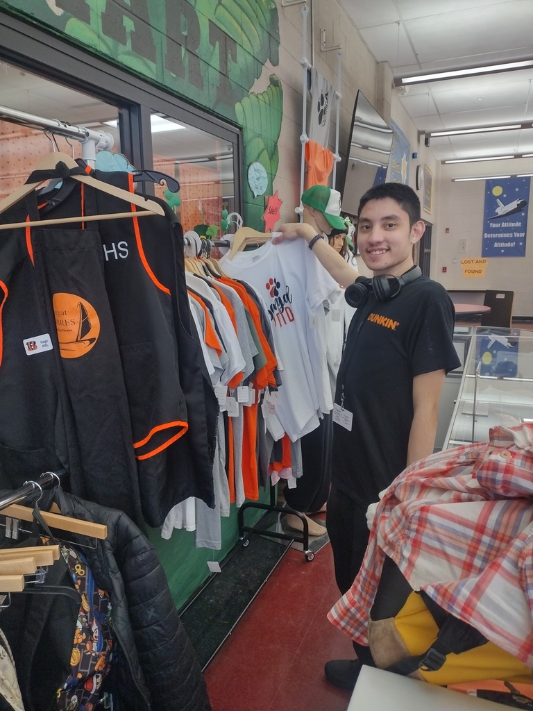 Image of Dominic hanging a t-shirt on a clothing rack that has all of the clothing items for sale at CLAWMART. 