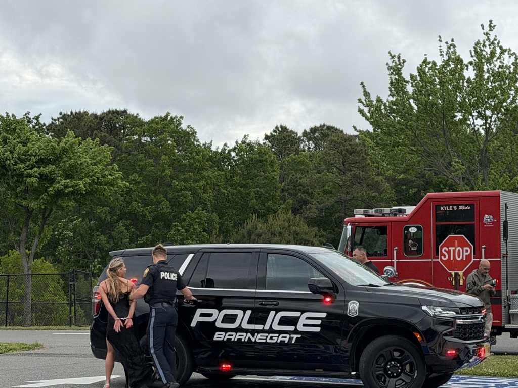 Image of the student actor who was driving being taken to the police car in handcuffs.