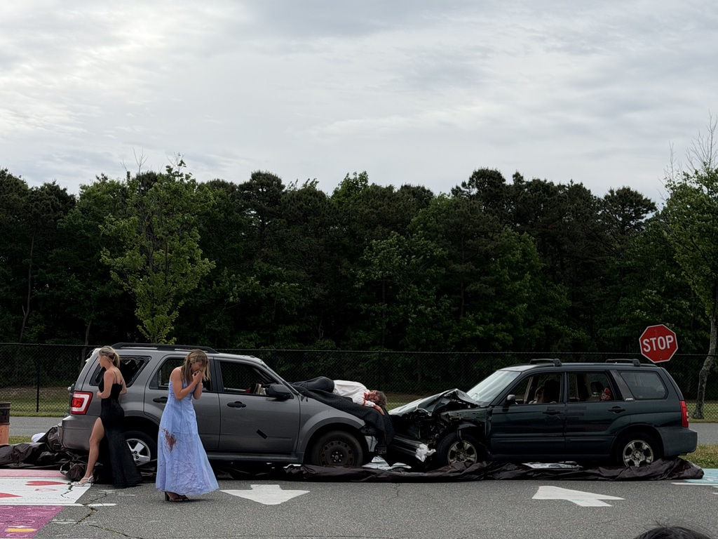 Image of the student actors involved in the car crash. Two are outside the one car and one is on the hood of the car. In the second car there are three student actors.