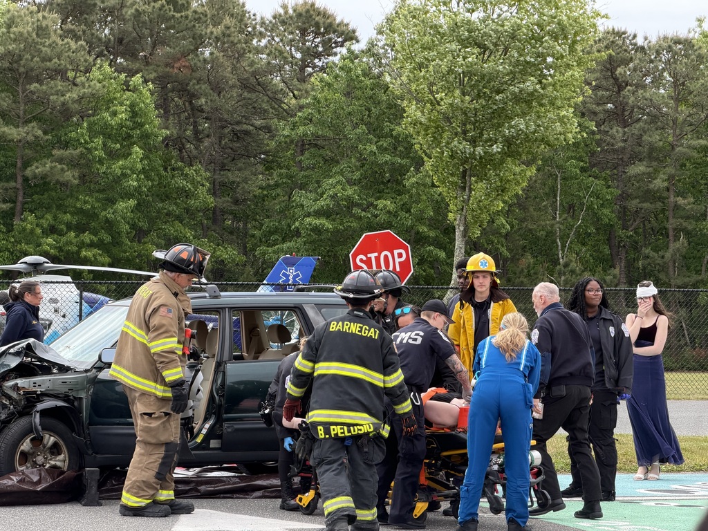 Image of a student actor on a stretcher surrounded by fire department workers and EMS workers.