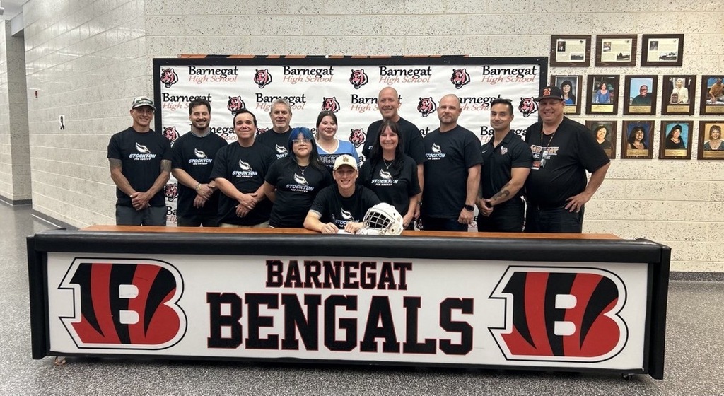 Image of DJ posing with his coaches, family, and Athletic Director. 