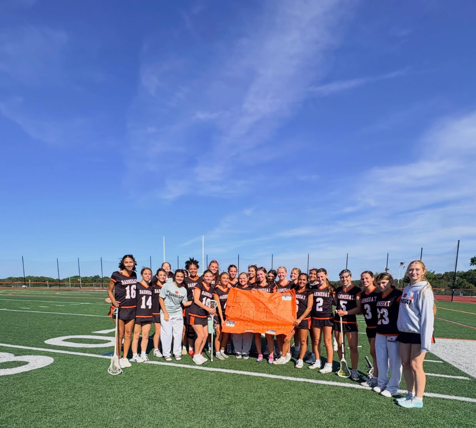 Image of Ella surrounded by the girls lacrosse team holding a sign in support of her 200th career point. 
