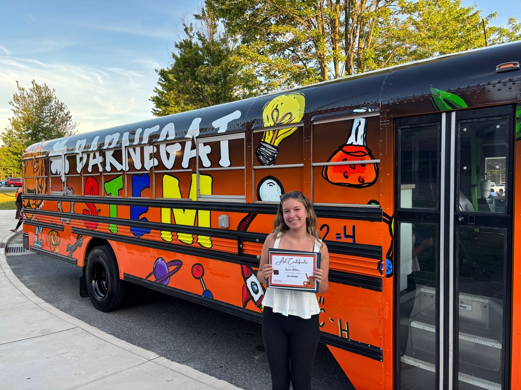 Image of Sophia standing in front of the STEM Bus holding a certificate of appreciation. 
