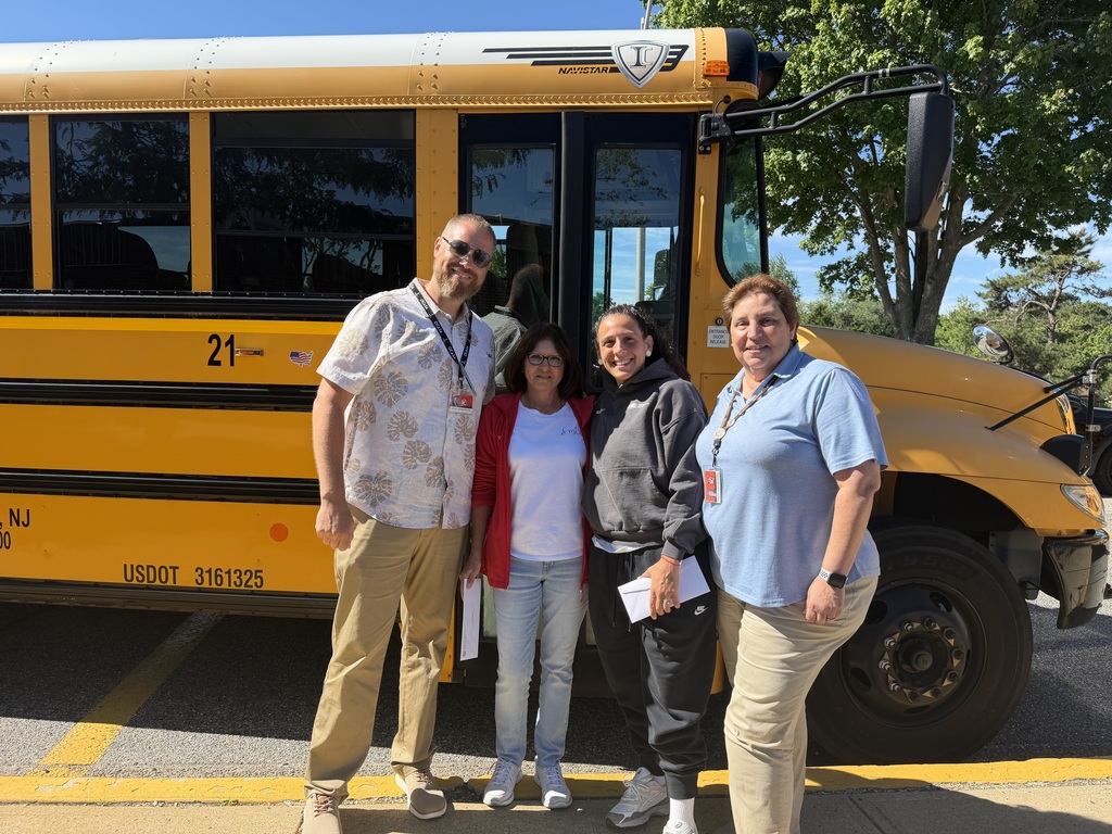 Image of Glenda and Christina posing in front of a bus with the Superintendent and Transportation Supervisor. 