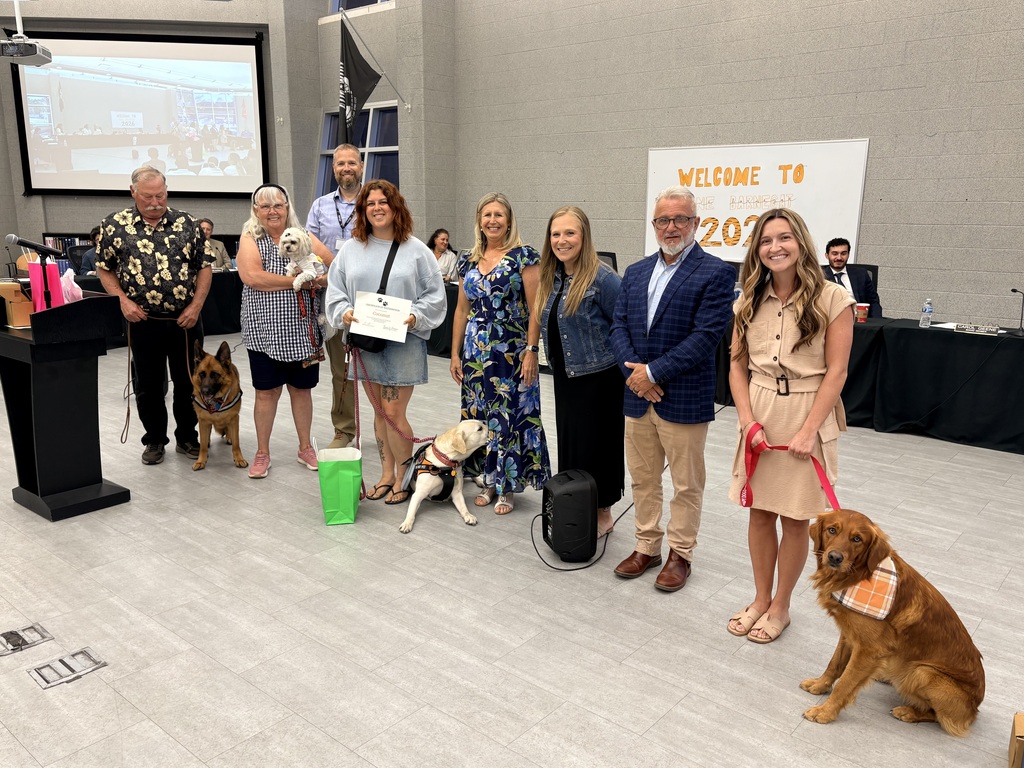 Image of four therapy dogs and their handlers posing with the Superintendent, Board President, and two counselors.