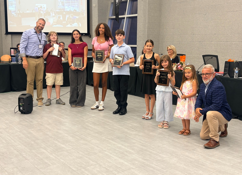 Image of the UPstanders holding their plaques, posing with the Superintendent and Board President.