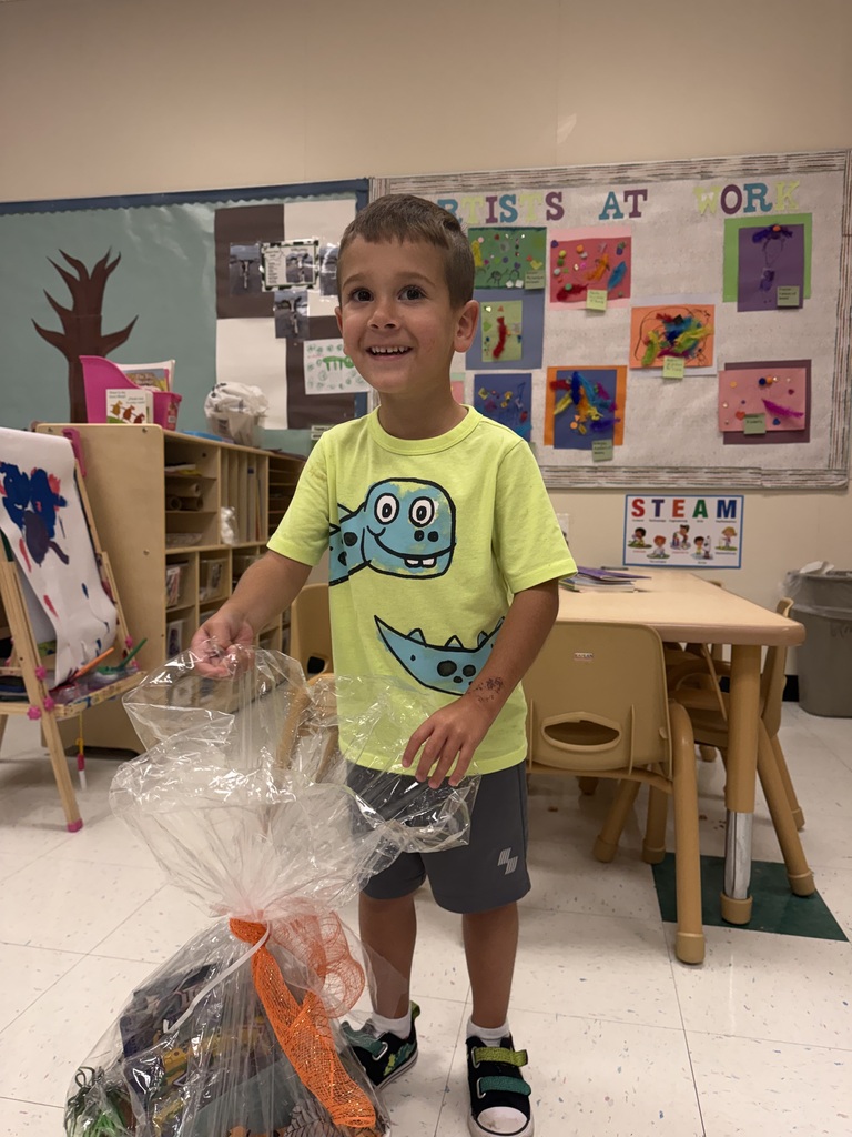 Picture of Austin standing behind the basket of items that he won.