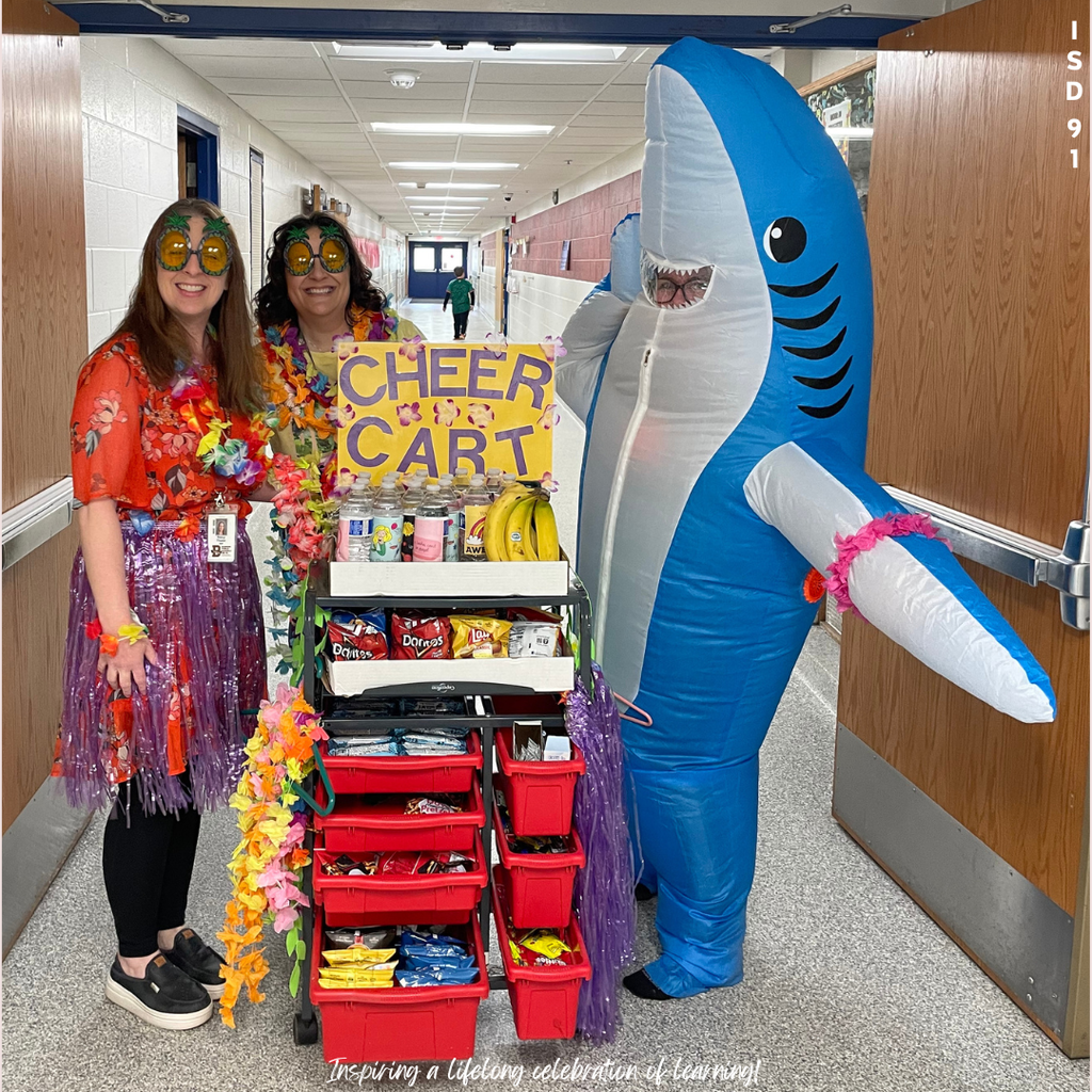 Staff dressed in Hawaiian clothing and in a shark suit with a Cheer Cart of goodies