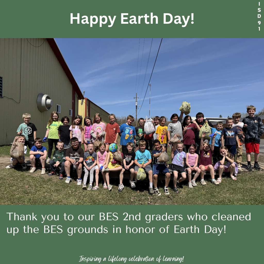 BES 2nd graders outside on school grounds by bus garage holding up bags of trash they picked up around the grounds