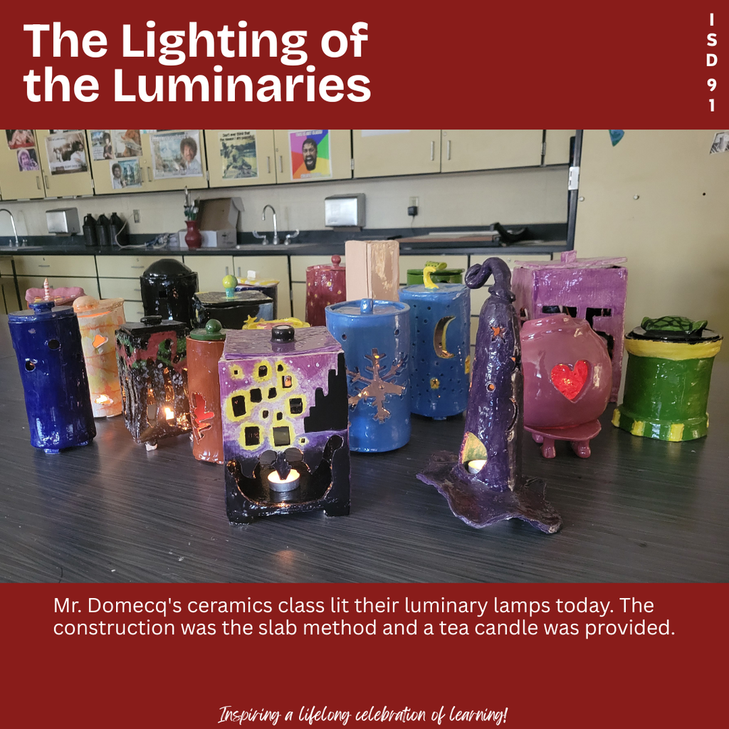 A table hosting lit luminaries made by the ceramics class.
