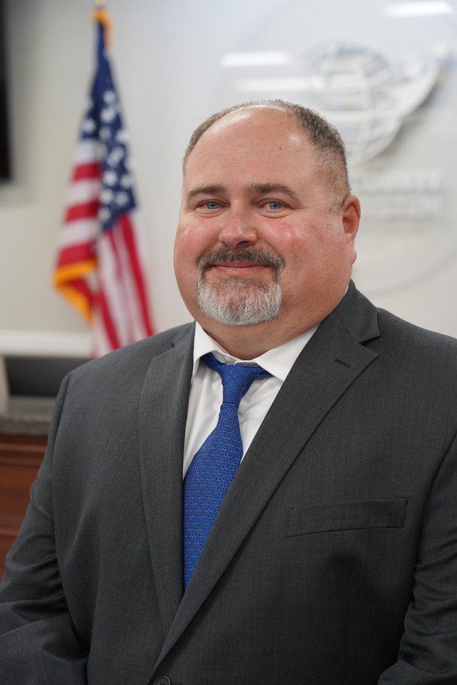 man standing in a board room next to flag