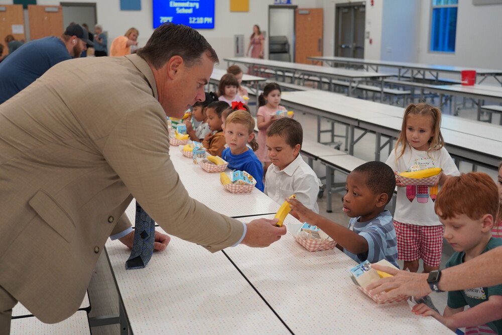 man giving banana to child in cafeteria