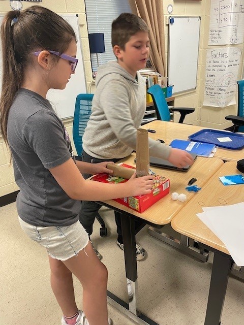 4th grade students collaborating with each other on how to build a harp.