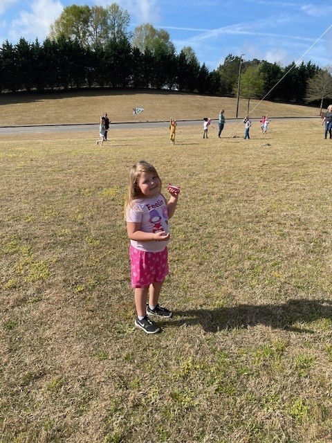 A student flying a kite outside for Kite Day.