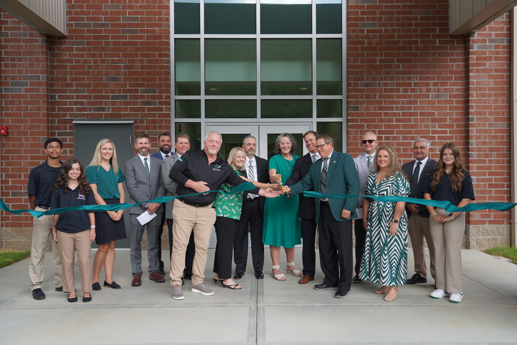teachers and administrators cutting a ribbon to a new addition