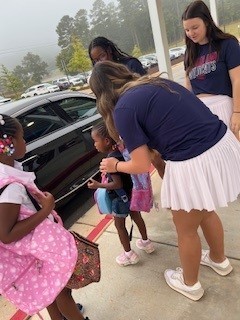 Woodland cheerleader helping a student out of a car