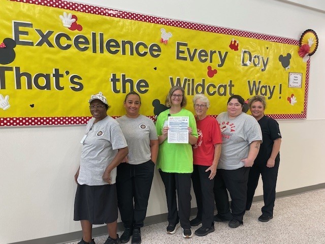 Our lunchroom staff earned a 100 on our health inspection. They are smiling for a picture. 