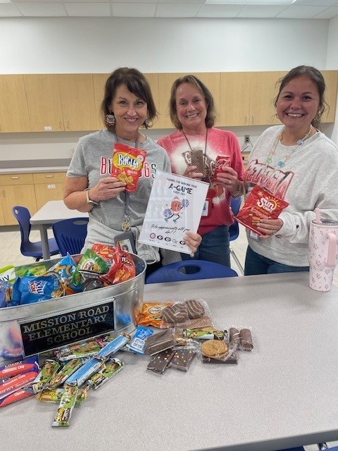 Staff smiling for a picture on spirit day and receiving a sweet treat. 