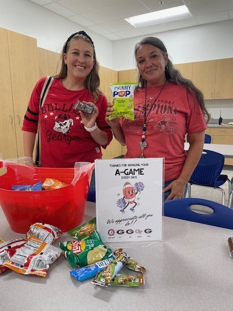 Teachers smiling for a picture while getting a sweet treat. 