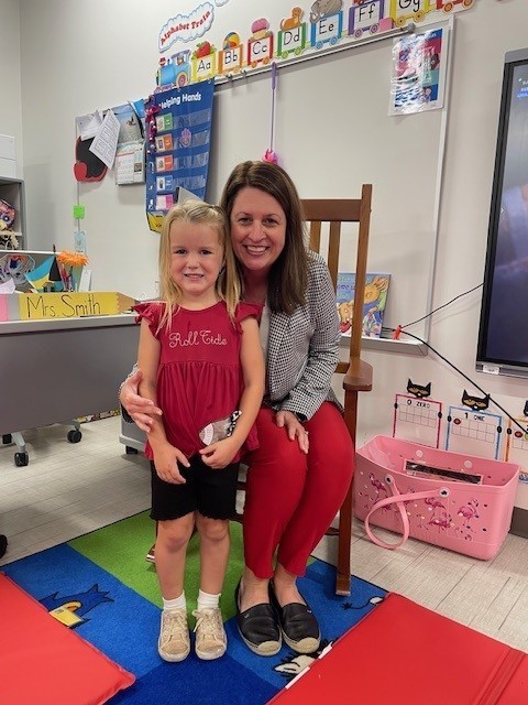 Principal smiling with a PreK student for spirit day.
