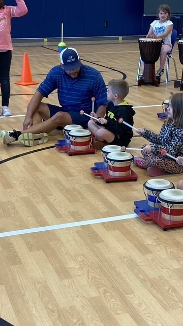 Teacher helping a student during the dancing drum presentation.