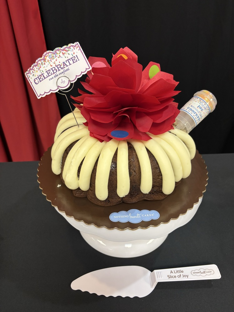 a nothing Bundt cake and spatula are sitting on a pedestal on a black table cloth