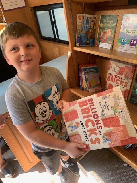 boy holding up a book in the book mobile