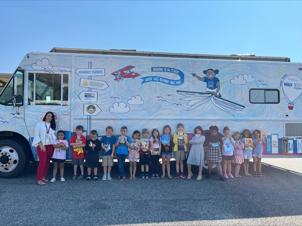group of students holding books in front of book mobile