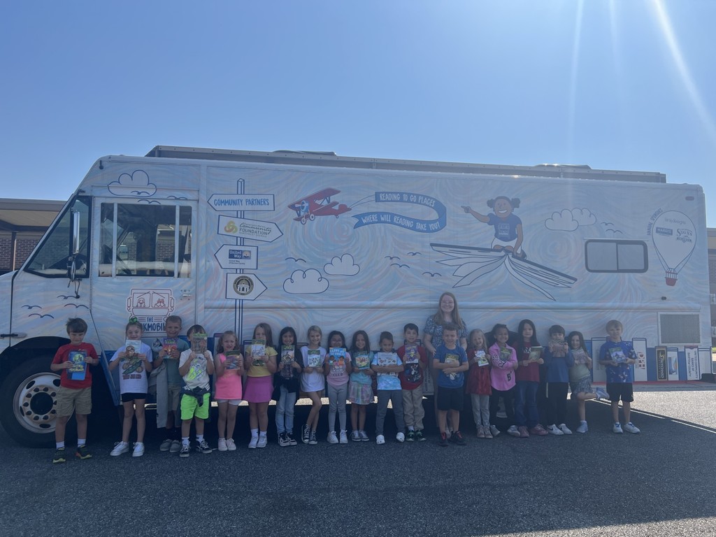group of students holding books in front of book mobile